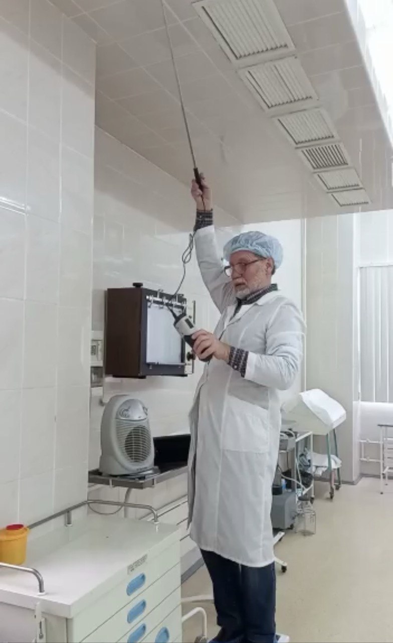 Специалист измеряет параметры вентиляции прибором
